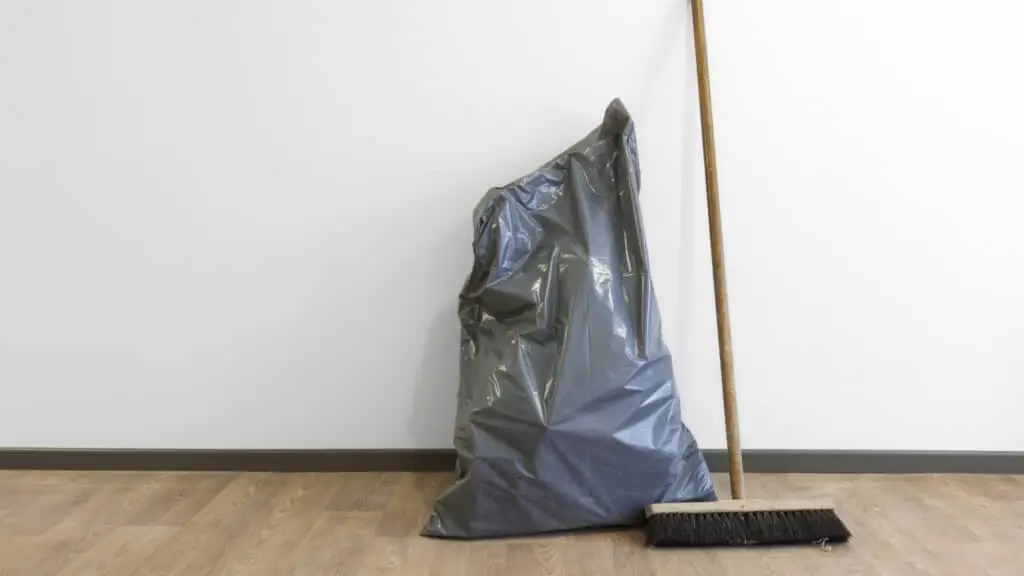 Ein Besen und ein Müllsack in einer leeren Wohnung